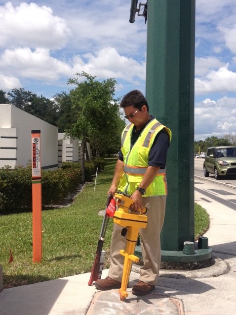 man locating fiber cable in front of signal cabinet