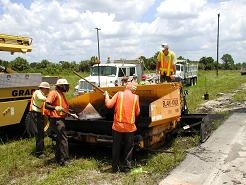 Patch 4, Crew putting asphalt on road to repair.